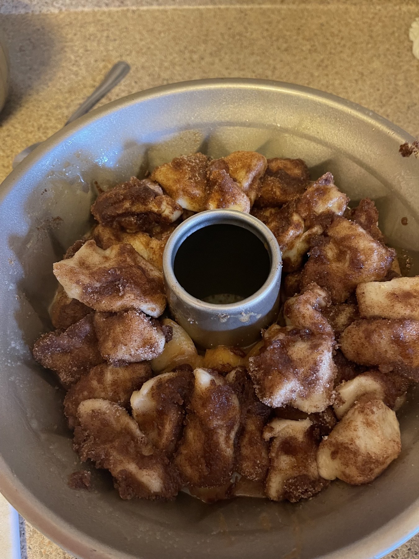 Bundt pan filled with cinnamon-sugar dough pieces and apple filling, ready to bake