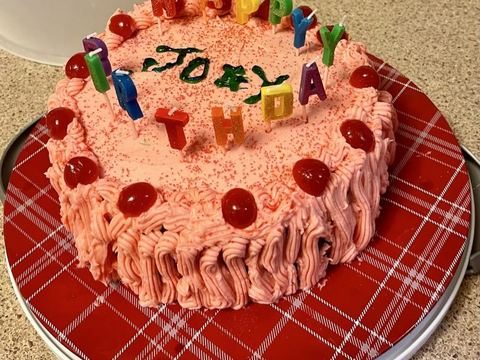Pink birthday cake with candles and cherries