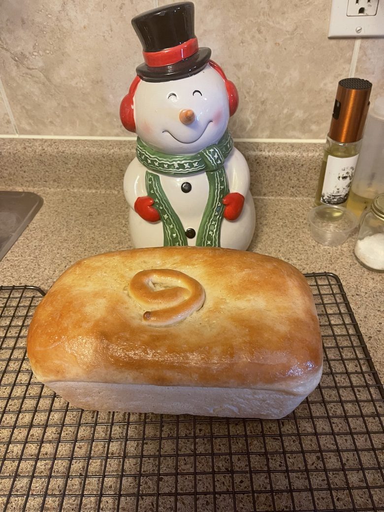 Golden loaf with a decorative baked-in swirl and a snowman cookie jar behind it