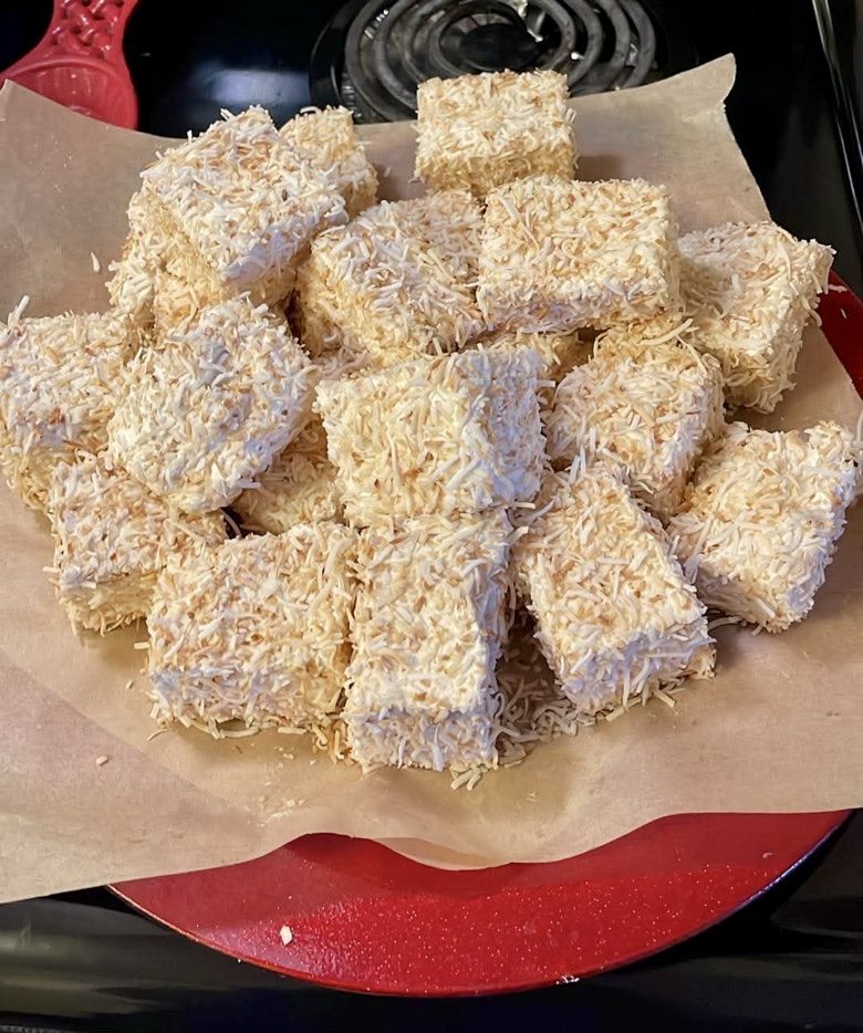 Coconut-covered marshmallow squares piled on a red plate