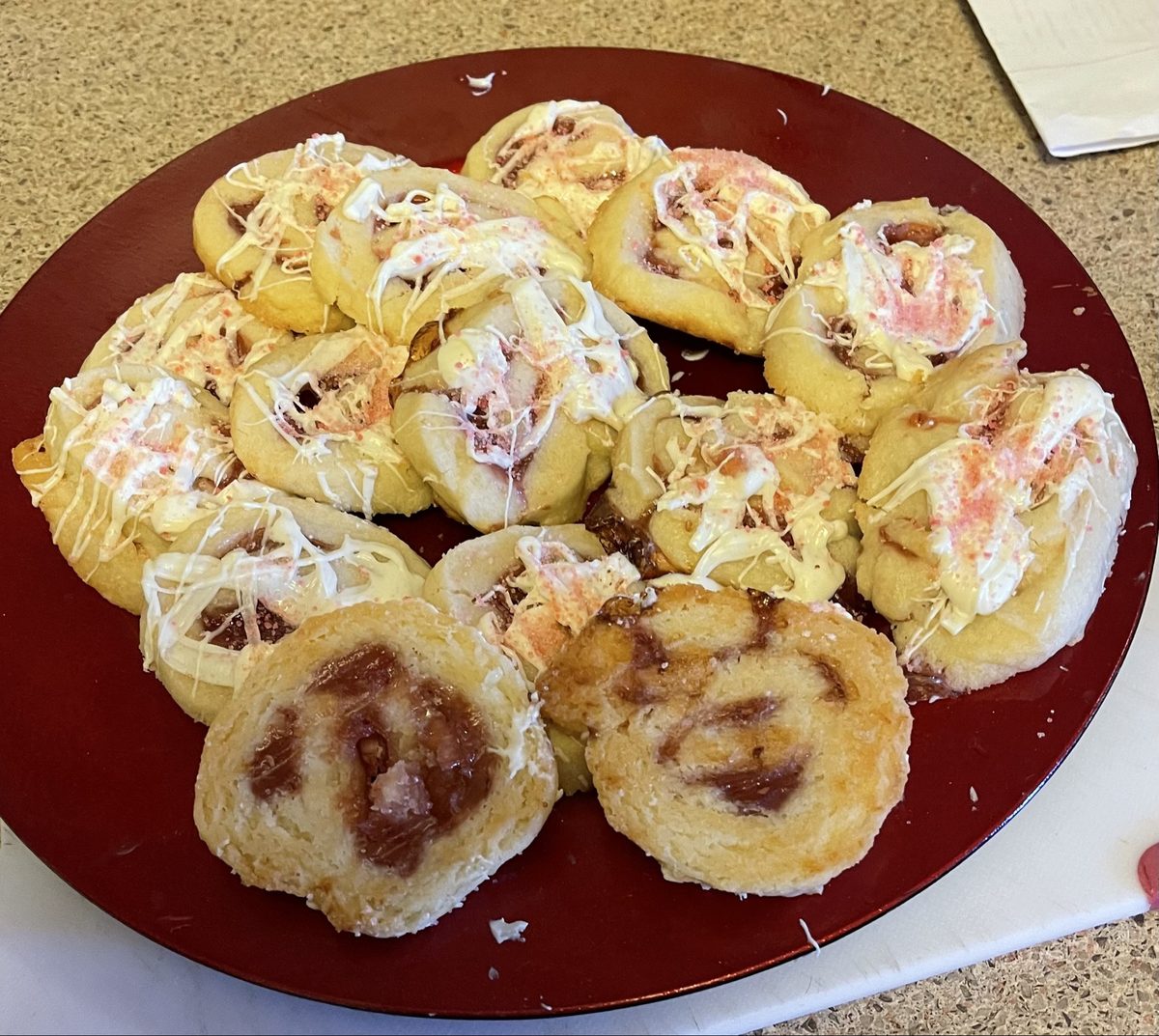 Raspberry swirl shortbread cookies with white chocolate drizzle on a red plate