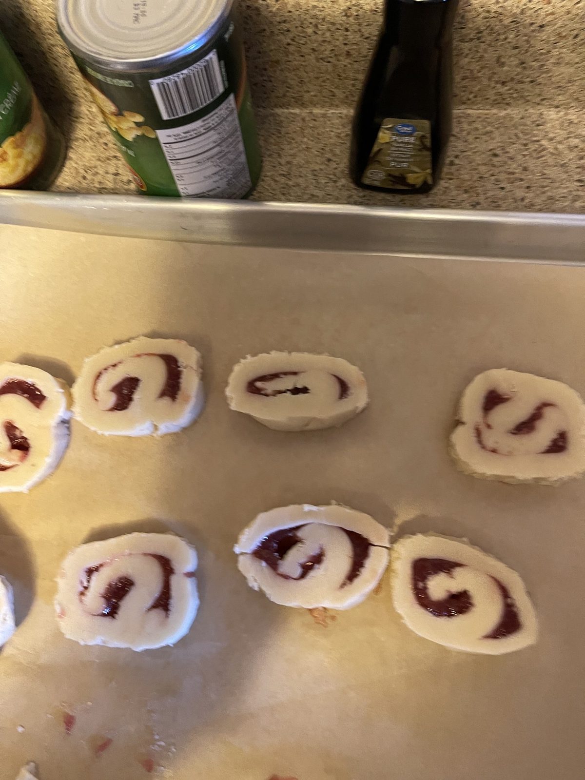 Unbaked raspberry swirl cookie rounds arranged on a parchment-lined baking sheet