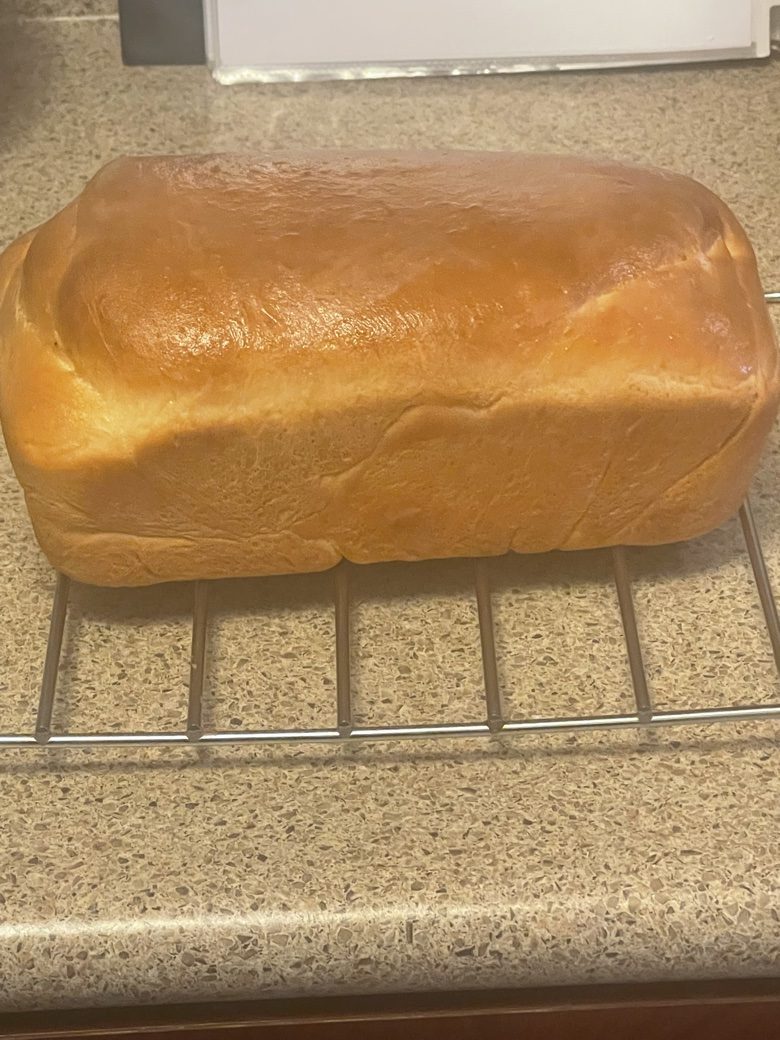Fresh-baked sandwich loaf cooling on a rack