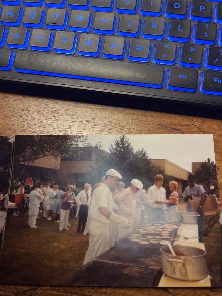 Bob in a pink shirt working the grill at the hospital barbecue